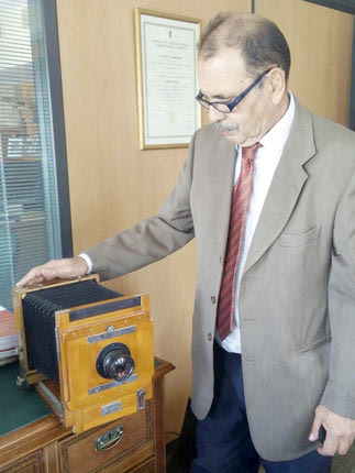 Ο Αντώνης Δαμανάκης ακουμπά στη φωτογραφική μηχανή που απαθανάτιζε πριν δεκαετίες τους Ηρακλειώτες στα πάρκα