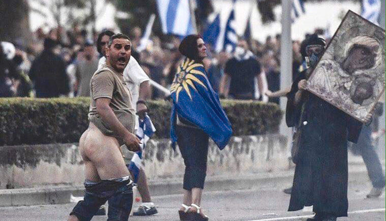 νας άντρας με κατεβασμένα παντελόνια μπροστά σε μια καλόγρια με μάσκα και την εικόνα της Παναγιάς στη ΔΕΘ