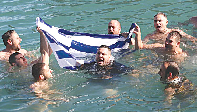 Βουτηχτάδες που έπεσαν στα παγωμένα νερά του ενετικού λιμανιού τα Θεοφάνια στο Ηράκλειο, μετά την ανάσυρση του σταυρού ξεδίπλωσαν μέσα στη θάλασσα την ελληνική σημαία.