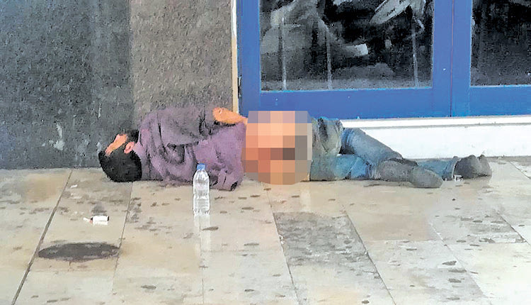 Ένας άνθρωπος πεσμένος στο έδαφος, αβοήθητος, με κατεβασμένα τα ρούχα του έξω από τον κινηματογράφο Αστόρια