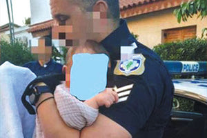 H φωτογραφία με τον αστυνομικό που κρατάει στην αγκαλιά του το μωρό της οικογένειας μετά τη δολοφονία της εικοσάχρονης μητέρας του