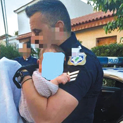 H φωτογραφία με τον αστυνομικό που κρατάει στην αγκαλιά του το μωρό της οικογένειας μετά τη δολοφονία της εικοσάχρονης μητέρας του