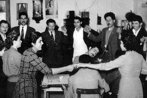 ΦΩΤΟΗΜΕΡΑΣ: Το κέφι της παρέας στο έπακρο χορεύοντας γύρω από τους οργανοπαίκτες αδελφούς Χατζογιαννάκη, Μιχάλης βιολί και Ζαχαρίας λαγούτο, στην βραδιά της εθνικής εορτής της 25ης Μαρτίου, 25/3/1957, στο καφενείο του Ιωάννη Περβολαράκη. Διακρίνονται από δεξιά: Ευαγγελία Κοντογιάννη-Καγιαμπάκη με τον σύζυγό της Κωνσταντίνο, Θρασύβουλος Εμμ. Χανιωτάκης, Εμμανουήλ Ν. Ανδρουλάκης λυράρης, Εμμανουήλ Κ. Τζενάκης, Ζαχαρίας Εμμ. Βουράκης, Δημήτριος Μιχ. Καγιαμπάκης με τη σύζυγό του Μαρίκα, άγνωστη, Στεφανούλα Νικ. Βελιγραντάκη, Πιπίτσα Κοντογιάννη-Βασιλάκη και Μαρίκα Βουράκη-Τζενάκη (Πηγή: Πολιτιστικός Σύλλογος Αβδού).