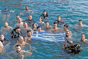 Συγκινητική ήταν η στιγμή που όλοι οι βουτηχτάδες, κρατώντας μέσα στα αγιασμένα ύδατα την ελληνική σημαία, έψαλαν τον εθνικό μας ύμνο