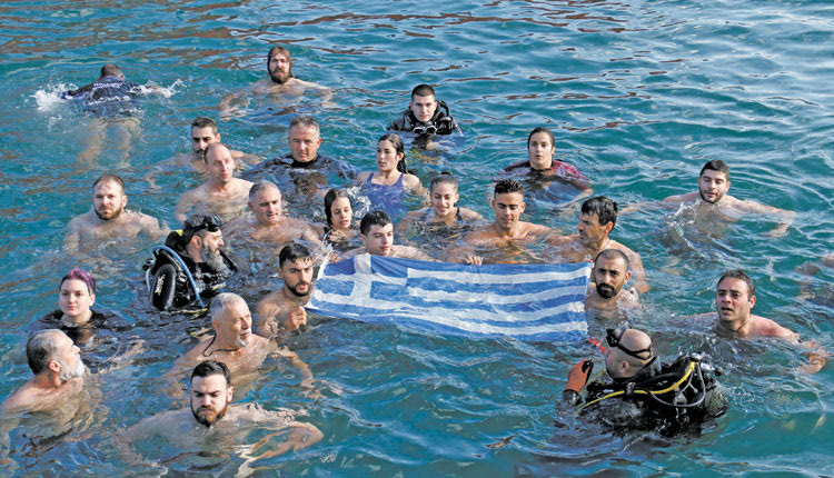 Συγκινητική ήταν η στιγμή που όλοι οι βουτηχτάδες, κρατώντας μέσα στα αγιασμένα ύδατα την ελληνική σημαία, έψαλαν τον εθνικό μας ύμνο