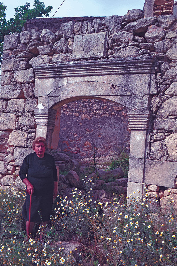 Η Δήμητρα Λαμπρινού – Καλλέργη στέκεται μπροστά στο ερειπωμένο σπίτι του πατέρα της, Ιωάννη Καλλέργη του Ιωάννου. Ο Ιωάννης Καλλέργης εκτελέστηκε στον Γουρνόλακκο στις 5 Σεπτεμβρίου 1943. Τα σπίτια των 22 Αβδελλιανών που εκτελέστηκαν στον Γουρνόλακκο εγκαταλείφθηκαν στη φθορά του χρόνου. 