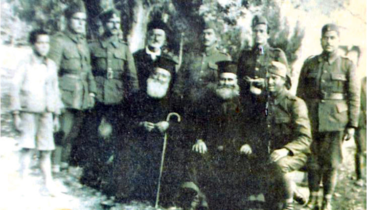 Νεάπολη Λασιθίου, περιοχή Αγίου Γεωργίου Ψαθά, Σεπτέμβριος 1940. Επίστρατοι του νομού Ηρακλείου στρατοπεδεύουν εκεί πριν την κήρυξη του πολέμου. Ο Γεώργιος Χαραλαμπάκης διακρίνεται στα γόνατα, δίπλα στους ιερείς δεξιά