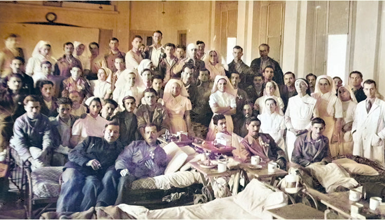 13ο Στρατιωτικό Νοσοκομείο Αθηνών (Πολυτεχνείο). Ο Γεώργιος Χαραλαμπάκης αναρρώνει μετά την εγχείρηση και την αποκοπή των κάτω άκρων του στο στρατιωτικό Νοσοκομείο Ιωαννίνων. Ο Γεώργιος Χαραλαμπάκης διακρίνεται στο μέσον ακριβώς της φωτογραφίας, μεταξύ δύο νοσοκόμων και ενός συντρόφου του