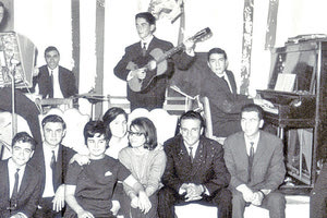 ΦΩΤΟΗΜΕΡΑΣ: Απόκριες 1963, Λιμενικό Περίπτερο. Ορχήστρα (από αριστερά): Γιάννης Περτσελάκης - ακορντεόν, Μίμης Τρικουράκης - ντραμς, Τίτος Πετράκης – κιθάρα, Βαγγέλης Σαμαράκης –πιάνο. Κάτω, από αριστερά: Λεωνίδας Φανουράκης, Γιώργος Βερνάρδος, Άννα Νιώτη, Νασούλα Μπαρμπαρήγου, Μπούλη Φαμελιάδου, Μανώλης Χατζηαδάμ, άγνωστος, άγνωστος. B.Σ.