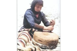 Κρητικιά αλέθει σιτάρι στον πέτρινο χειρόμυλο